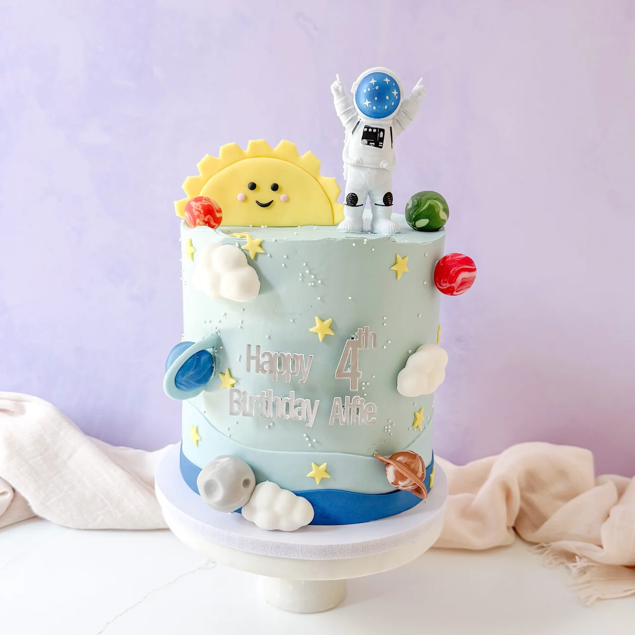 A handmade astronaut cake with a smiling sun and tiny planets